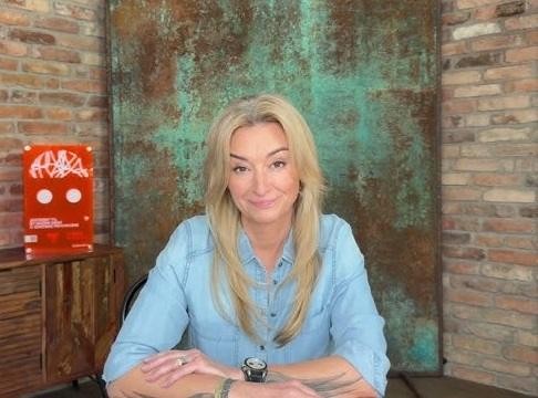 Martyna Wojciechowska podczas podróży, w otoczeniu naturalnym, symbolizującym jej działalność podróżniczą i społeczną.