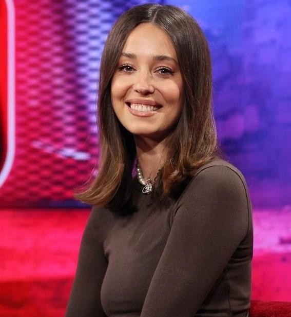 Izabella Krzan w studiu telewizyjnym, dynamicznie prezentująca program, podkreślająca jej rolę jako charyzmatycznej prezenterki.