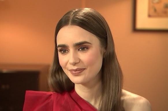 Lily Collins na planie filmowym, w trakcie pracy nad sceną lub przeglądająca scenariusz, z widocznymi elementami otoczenia filmowego, ukazująca jej zaangażowanie i profesjonalizm.