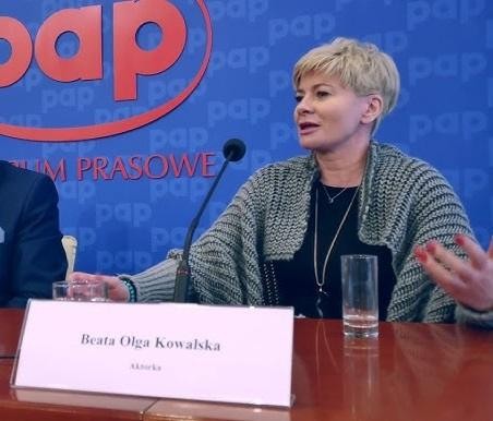 Beata Olga Kowalska na scenie teatralnej, w świetle reflektorów, ukazująca swoją pasję i ekspresję aktorską.